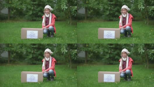 自信积极的青少年生态活动家坐在公园的盒子与回收标志手势拇指向上看相机。白种人少女在秋春的一天在户外与垃圾摆姿势高清在线视频素材下载
