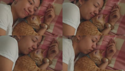 亚洲妇女睡觉和拥抱小猫小猫在家里的床上。高清在线视频素材下载