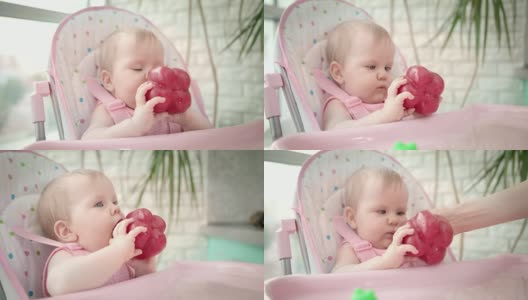 婴儿在椅子上啃红辣椒。婴儿蔬菜的饮食。儿童健康营养高清在线视频素材下载