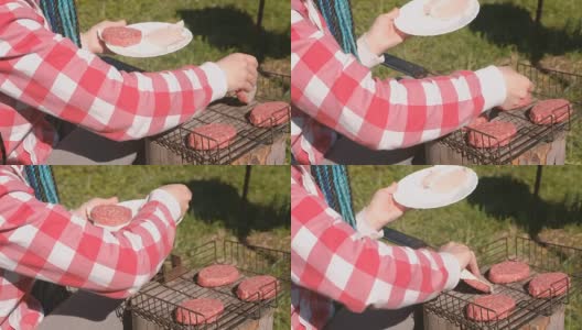 年轻女子把肉排放在烤架上。特写镜头。她穿着粉红色的格子衬衫，梳着蓝色的辫子。高清在线视频素材下载