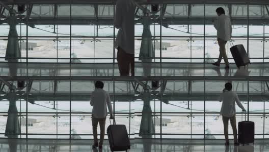 4 k。男性年轻乘客使用智能手机带着行李箱在机场候机楼出发区行走。穿着休闲装出差的亚洲商人。现代旅游生活理念。高清在线视频素材下载
