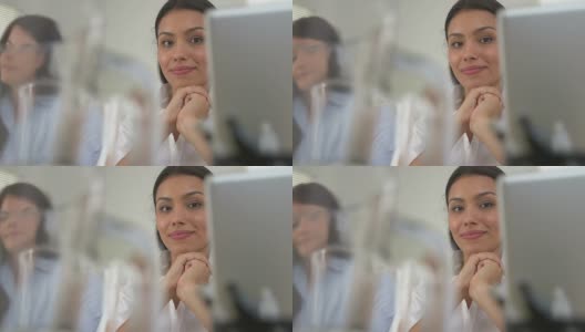 西班牙裔女商人微笑着，背后是同事高清在线视频素材下载