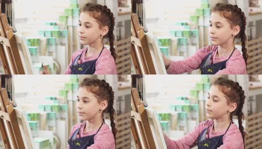 一个可爱的小女孩在学校画架上的特写高清在线视频素材下载