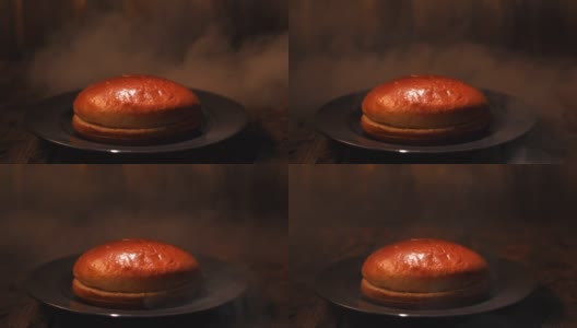 木桌子上放着一个黑色玻璃盘子里的汉堡面包，背景是水蒸气。资料片。特写镜头高清在线视频素材下载