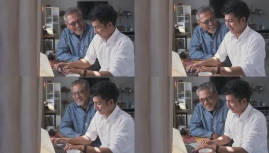 亚洲老父亲和他成年的儿子坐在家里使用笔记本电脑高清在线视频素材下载