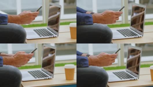 商人使用手机工作在笔记本电脑4k高清在线视频素材下载
