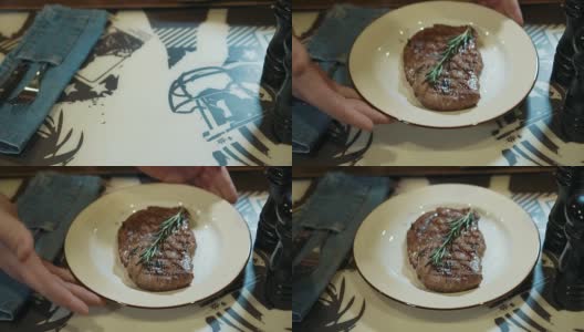在餐馆里，服务员正在把装着牛排的盘子放在桌子上高清在线视频素材下载