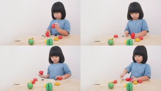 有趣的亚洲小女孩玩木制烹饪玩具，小厨师准备在厨房柜台上的食物高清在线视频素材下载