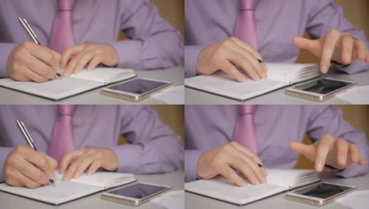 一个穿着紫色衬衫打着领带的商人在笔记本上做笔记。男人每天都写一支笔。一个人在记事本上做笔记。在办公室的办公桌上放笔记本电脑和智能手机。特写镜头。高清在线视频素材下载