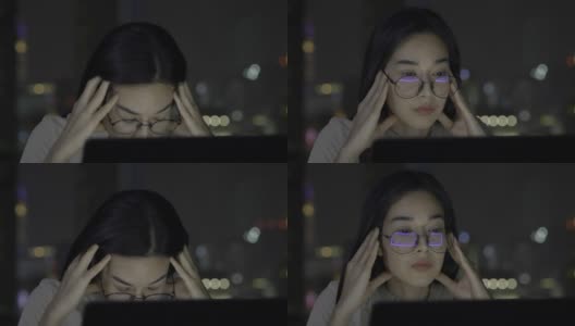 一个戴着眼镜，有思想的年轻女商人工作到深夜，因为不能看笔记本电脑而感到压力。高清在线视频素材下载