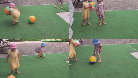 在炎热的夏天，快乐可爱的幼儿园小朋友们玩着五颜六色的球。孩子们在院子里玩耍。宝宝在花园在阳光明媚的一天户外。童年、职业、亲子、家庭观念高清在线视频素材下载