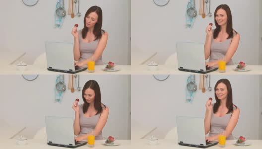 坐在笔记本电脑前吃草莓的女人高清在线视频素材下载