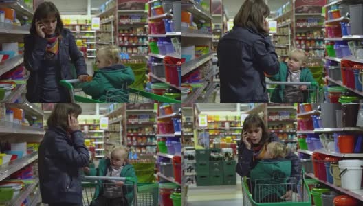 一位带着孩子的年轻妇女在超市选购商品。妈妈正用手推车载着一个小女孩。考虑器皿部门的货物。那个女人正在讲电话。高清在线视频素材下载
