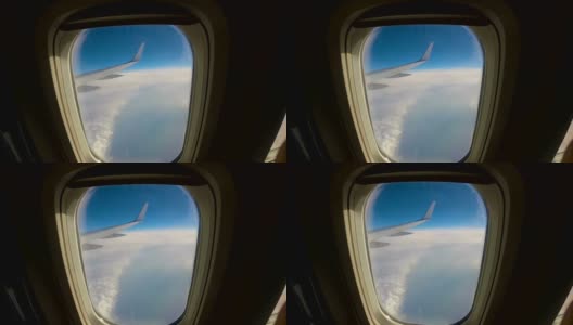 飞机飞过云层，透过窗户望向机翼的一架客机高清在线视频素材下载