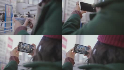 亚洲女孩喜欢这个城市，在公交车站等车的时候用智能手机拍照或录像。高清在线视频素材下载