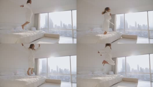 一个女人在酒店房间的床上跳。早上醒来，开始新的一天。曼谷的日出。慢动作高清在线视频素材下载