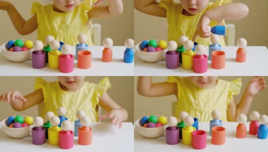 女孩通过玩一个小男人的彩色木制玩具来学习颜色，并把它们放在相应颜色的杯子里高清在线视频素材下载