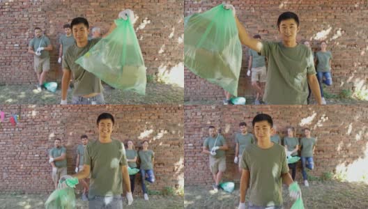 环境清理后，志愿者拿着垃圾袋站在志愿者队伍面前高清在线视频素材下载