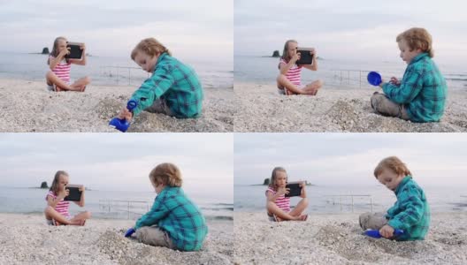 慢动作:男孩在沙滩上玩，女孩用触控板拍照高清在线视频素材下载