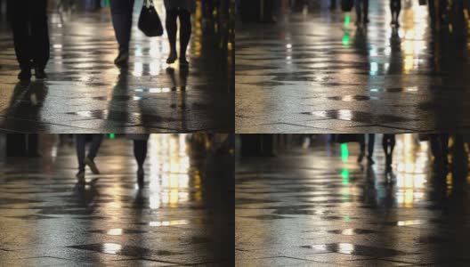 在潮湿的人行道上，街灯映出了辨认不出的人的剪影。长长的影子。雨夜的城市街道上有路灯，沥青路从雨中闪闪发光。不认识的行人，年轻人。夜晚的城市下雨。购物的概念高清在线视频素材下载