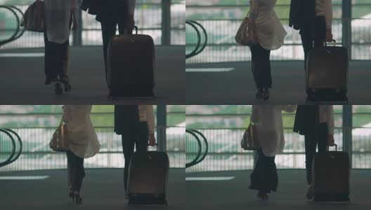 已婚夫妇走过机场天桥，男人提着行李箱，度假高清在线视频素材下载