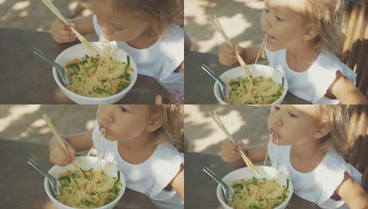 小女孩在露天的海滩咖啡馆用筷子吃面汤高清在线视频素材下载
