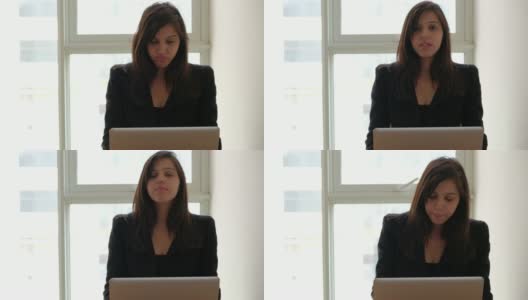 一名印度妇女在笔记本电脑上工作，她对着一个看着静态摄像头的同事说话高清在线视频素材下载