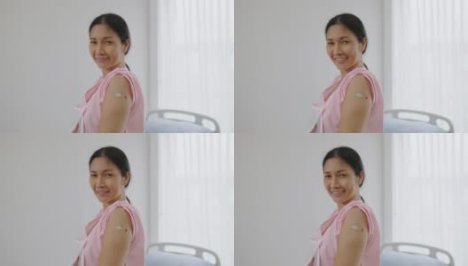 在医院里，一名亚洲老年妇女展示了她在接种新冠病毒疫苗后手臂上覆盖着的膏药，健康概念，健康保险，人寿保险，意外保险高清在线视频素材下载