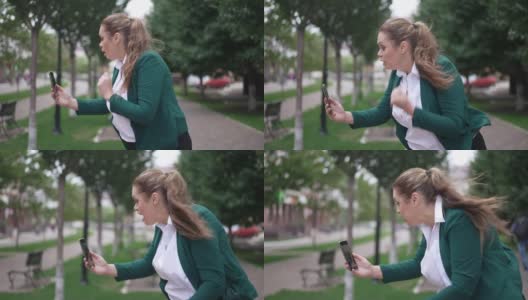 侧视图肖像愤怒的女博主手势说话的智能手机站在城市的街道上。不满的白人胖女人抱怨博客在线直播。高清在线视频素材下载