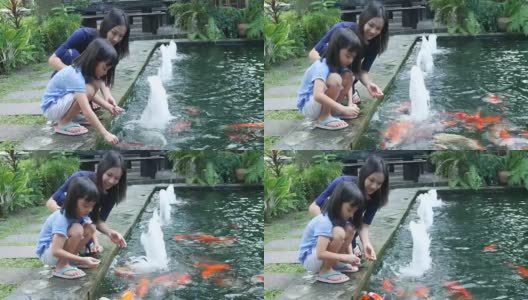 亚洲女孩和母亲在池塘里喂鲤鱼高清在线视频素材下载