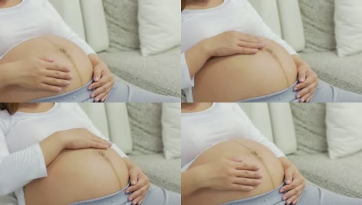 孕妇在客厅放松，双手触摸腹部高清在线视频素材下载