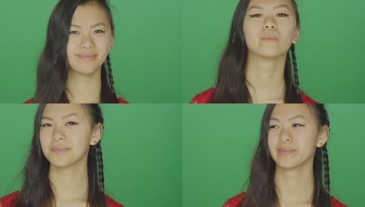 年轻的亚洲妇女环顾四周，微笑着，在一个绿色屏幕的工作室背景高清在线视频素材下载
