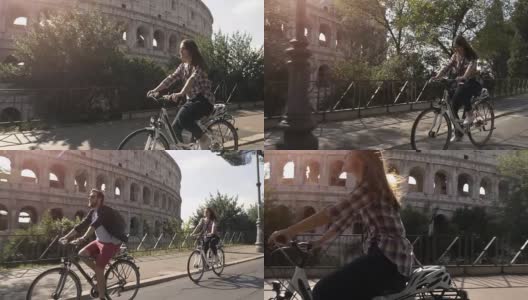 三个年轻的朋友游客在阳光明媚的日子里骑着自行车在罗马市中心的罗马斗牛场周围的道路上慢镜头摄影机汽车稳定摄影机高清在线视频素材下载