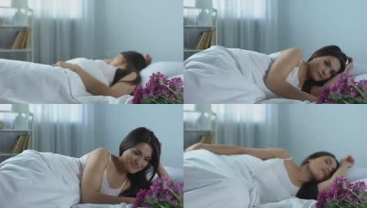 女人在床上醒来看到一束美丽的鲜花，惊喜万分高清在线视频素材下载