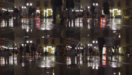 雨夜，在路灯的照耀下，雨点落在五颜六色的沥青上。不认识的人在雨伞下走，过有红绿灯的马路。美丽的彩色的散景。天气、交通、城市街道、现代城市生活方式的概念高清在线视频素材下载