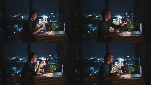 一个亚洲的中国美丽的年轻女士在她的公寓里吃甜点在神奇的时间，黄昏和她的男朋友通过互联网聊天用她的笔记本电脑高清在线视频素材下载
