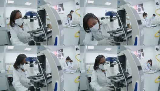 非裔美国女科学家在实验室工作，通过显微镜观察样本高清在线视频素材下载