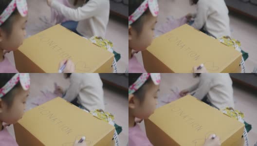 亚洲小孩写和画捐赠的盒子，衣服包装在家里高清在线视频素材下载