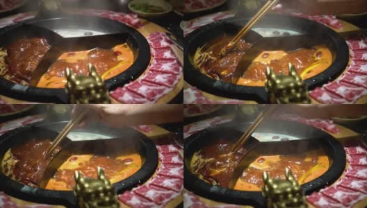 在中国的麻辣火锅汤里煮一片生猪肉高清在线视频素材下载