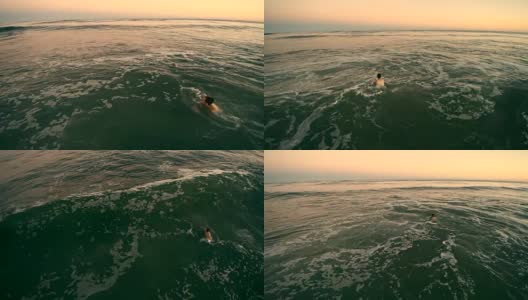 低空近距离航拍照片，这名年轻男子在日落时分的暴风雨中游泳。高清在线视频素材下载