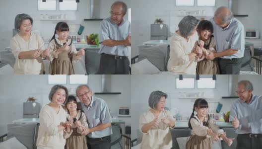 亚洲家庭小女孩和祖父母一起在客厅跳舞。儿童和老人和妇女用笑脸感受乐趣。可爱的家庭和活动理念的快乐时刻高清在线视频素材下载