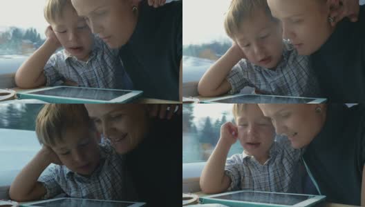 男孩和他的妈妈在平板电脑上看动画片高清在线视频素材下载