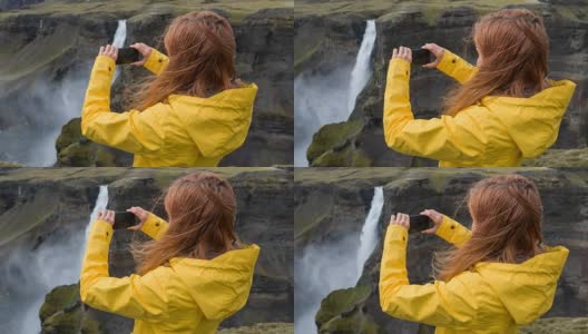 一名女子站在悬崖上，用智能手机拍摄瀑布高清在线视频素材下载