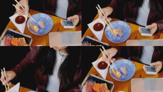一个女人在4k餐厅边吃寿司边玩手机高清在线视频素材下载