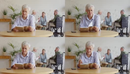 机架上聚焦了三个老人，其中两个男人包括一个坐轮椅的残疾人和一个女人，在养老院打牌聊天。聪明的老妇人坐在桌子前看书高清在线视频素材下载