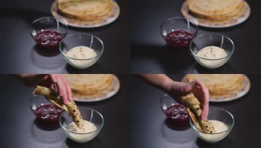 女孩的手拿起一个扭曲的煎饼，小心地蘸着酸奶油高清在线视频素材下载