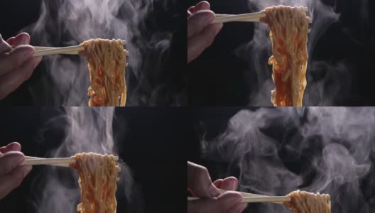 筷子美味面条与蒸汽和烟在黑暗的背景慢动作，亚洲餐的特写，热食物和快餐的概念高清在线视频素材下载