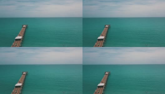 在朱诺海滩码头鸟瞰图，佛罗里达州与明亮的蓝色海水正午在春假期间在2021年3月高清在线视频素材下载