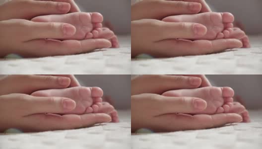 妈妈手里抱着宝宝的脚。新生儿在女性父母手中。小孩子的脚在妈妈的手掌里。特写镜头。孩子的小脚趾和快乐父母的女人的手。母亲节的节日。高清在线视频素材下载