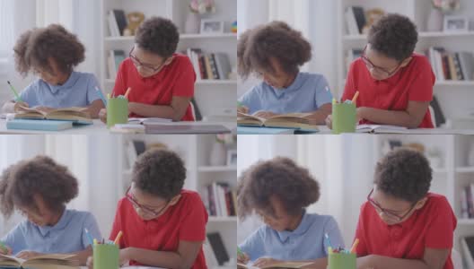 聪明的学童在笔记本上写字，戴眼镜的男孩有视力问题高清在线视频素材下载